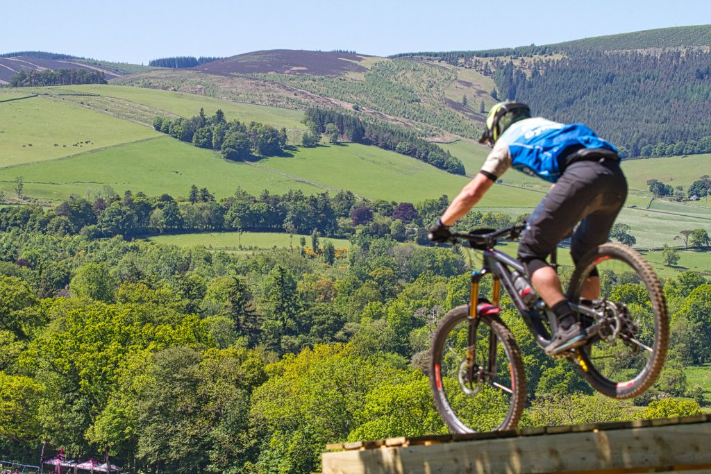 Competitor taking off from ramp enduro world series at Innerleithen